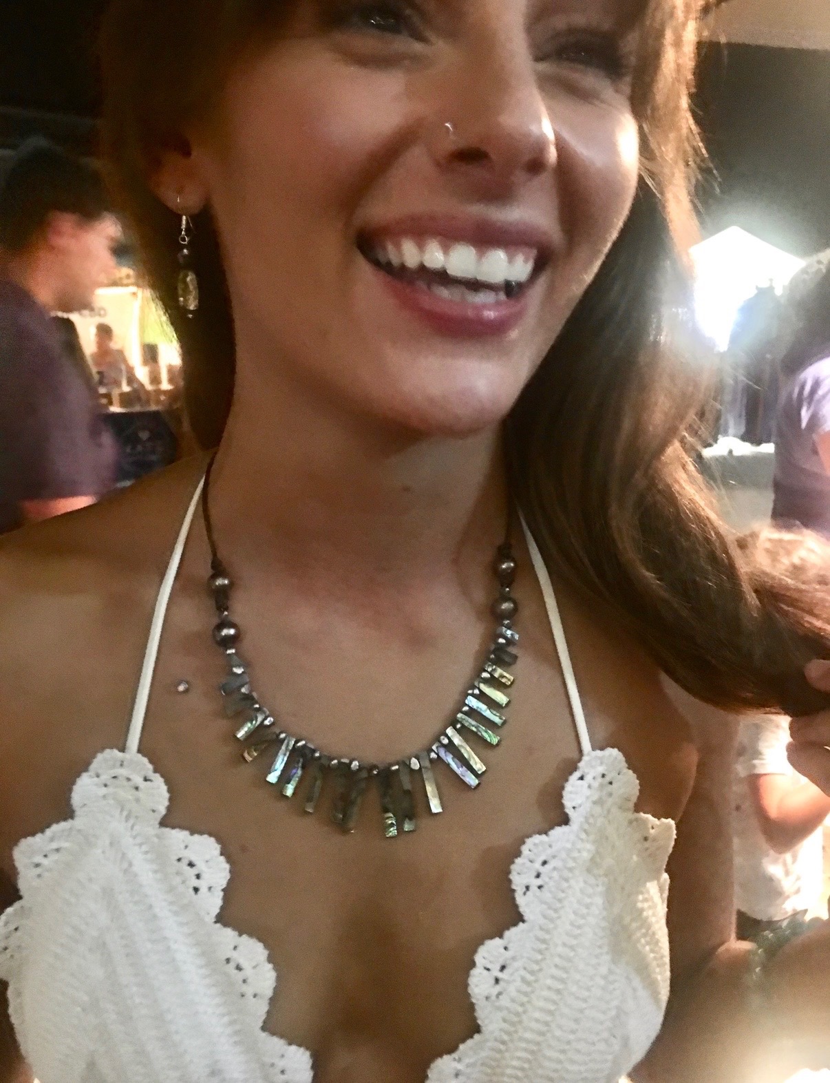 A smiling customer wearing a dark pearl and abalone necklace