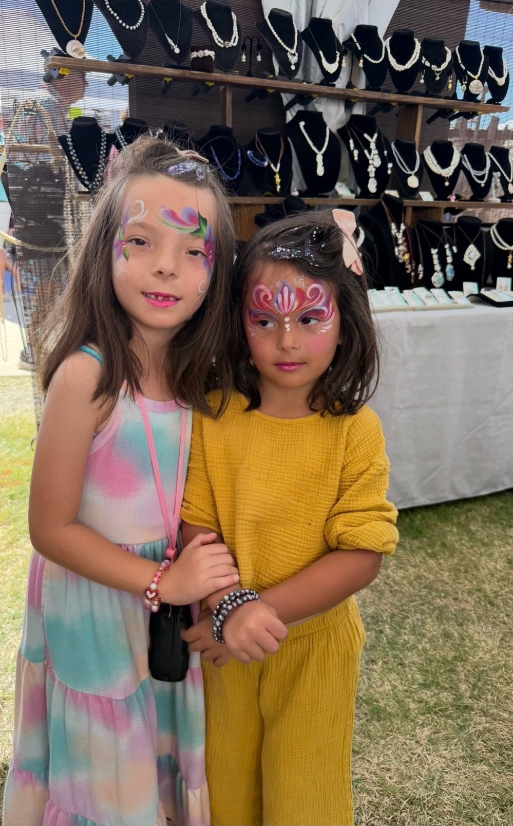 Two young festival visitors showing off their pearl bracelets